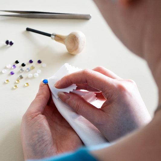 Woman holding gemstone stud earring which she is polishing with cloth
