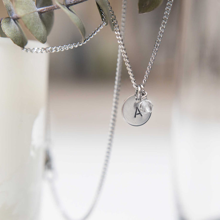 Initial necklace with birthstone charm hanging from branch
