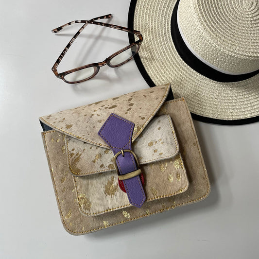 Beige handbag with purple strap, straw hat, and glasses on a light gray background