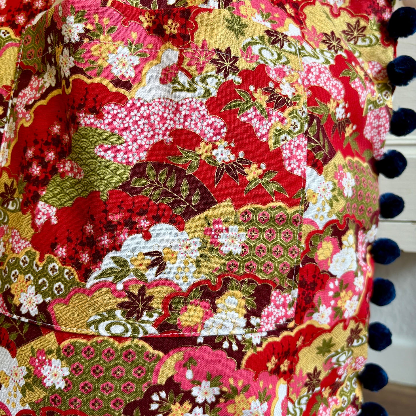 Colorful fabric with floral and geometric patterns and pom-pom trim.