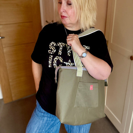 Woman holding a green bag indoors with wooden and white doors in the background