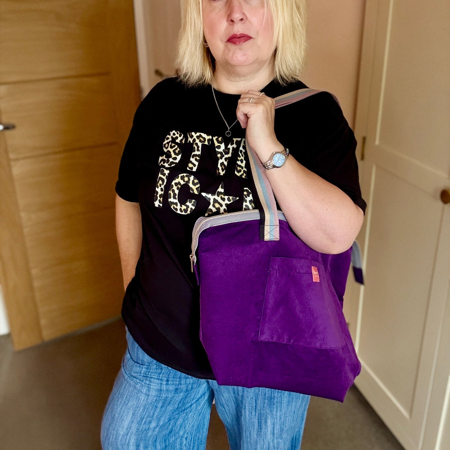 Person holding a purple bag indoors with wooden and white doors in the background