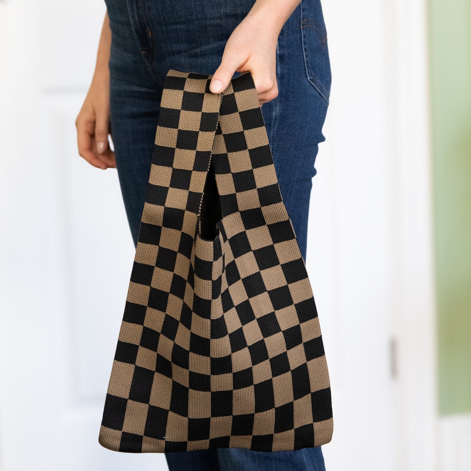 Person holding a checkered bag with a blurred background