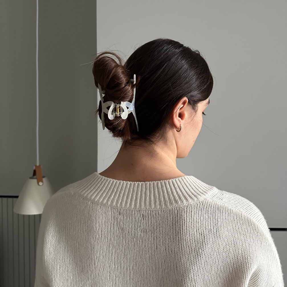 Woman with a hair clip in her bun against a gray wall