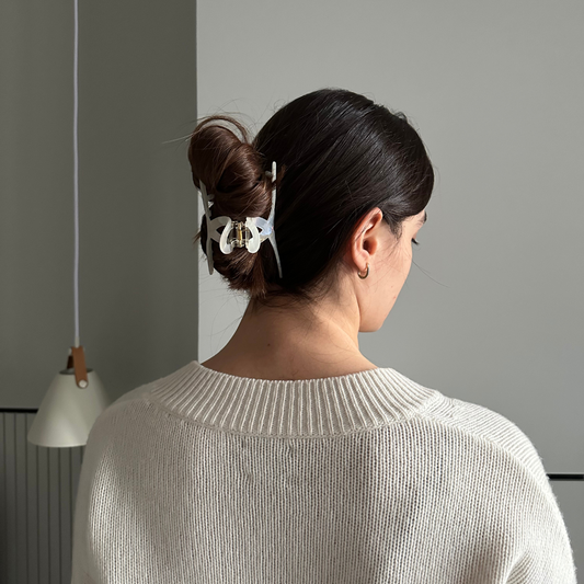 Woman with a hair clip in her bun against a gray wall