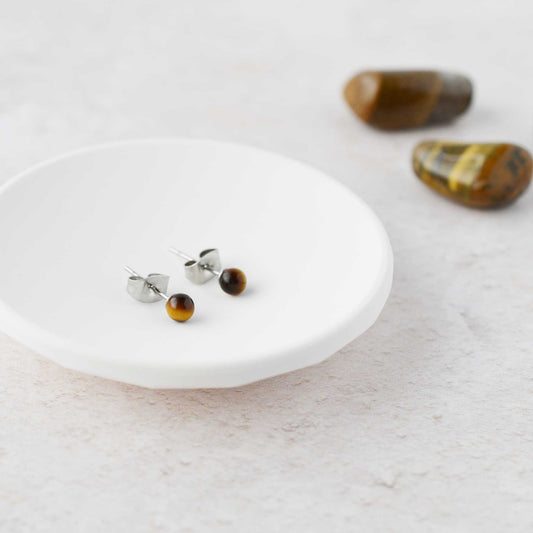 Tiny Tiger's Eye gemstone stud earrings in white trinket dish.