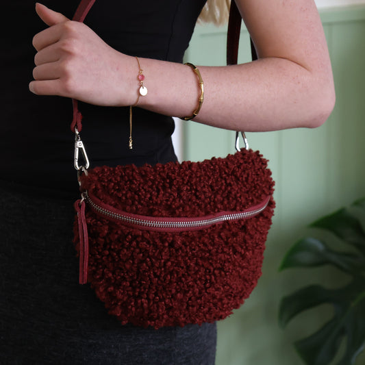 Red textured handbag held by a person with a blurred background