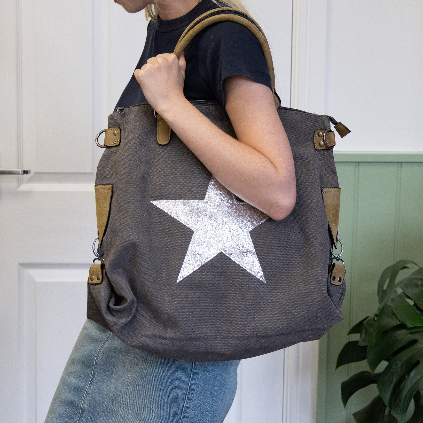 Person holding a large tote bag with a star design in front of a white door.