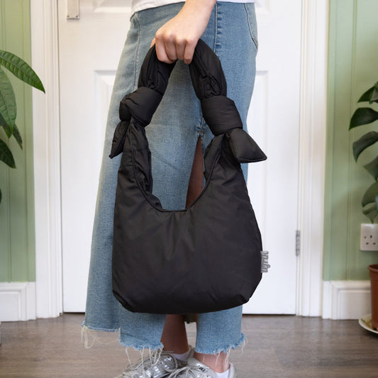 Person holding a black bag in a room with plants