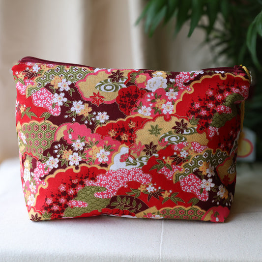 Floral patterned pouch on a white surface with a blurred plant in the background