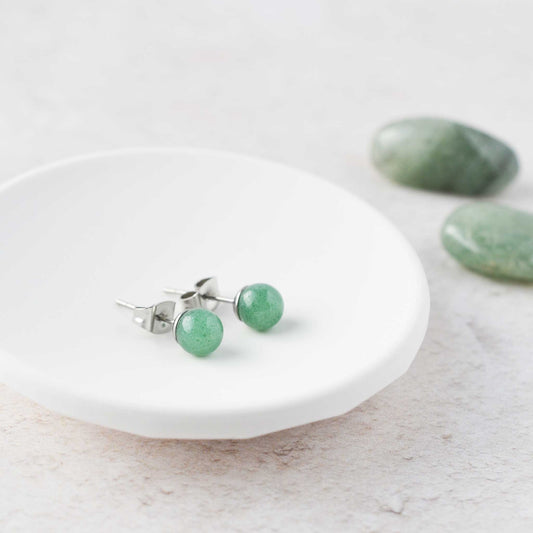 Simple round green aventurine gemstone stud earrings in white trinket dish.