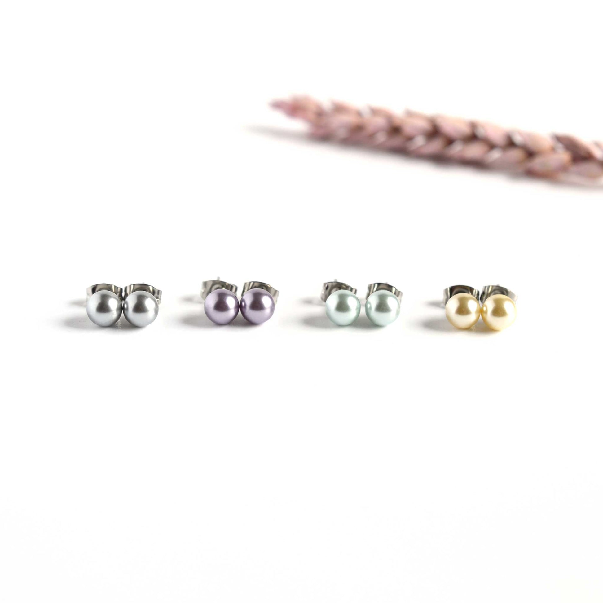 Four pairs of pastel coloured 6mm faux pearl stud earrings on white background