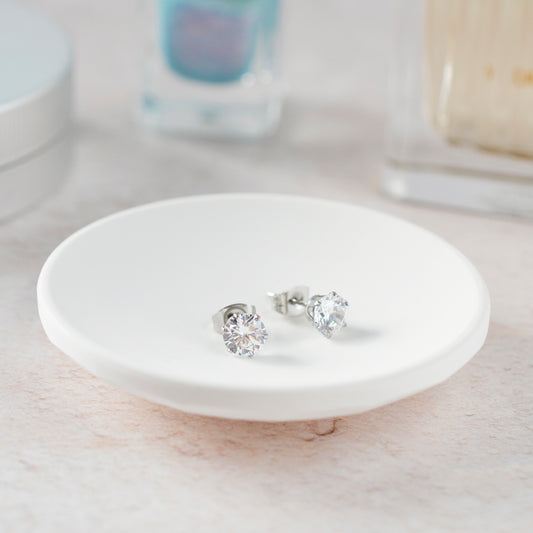 CZ Stud earrings on white trinket dish with soft focus background.