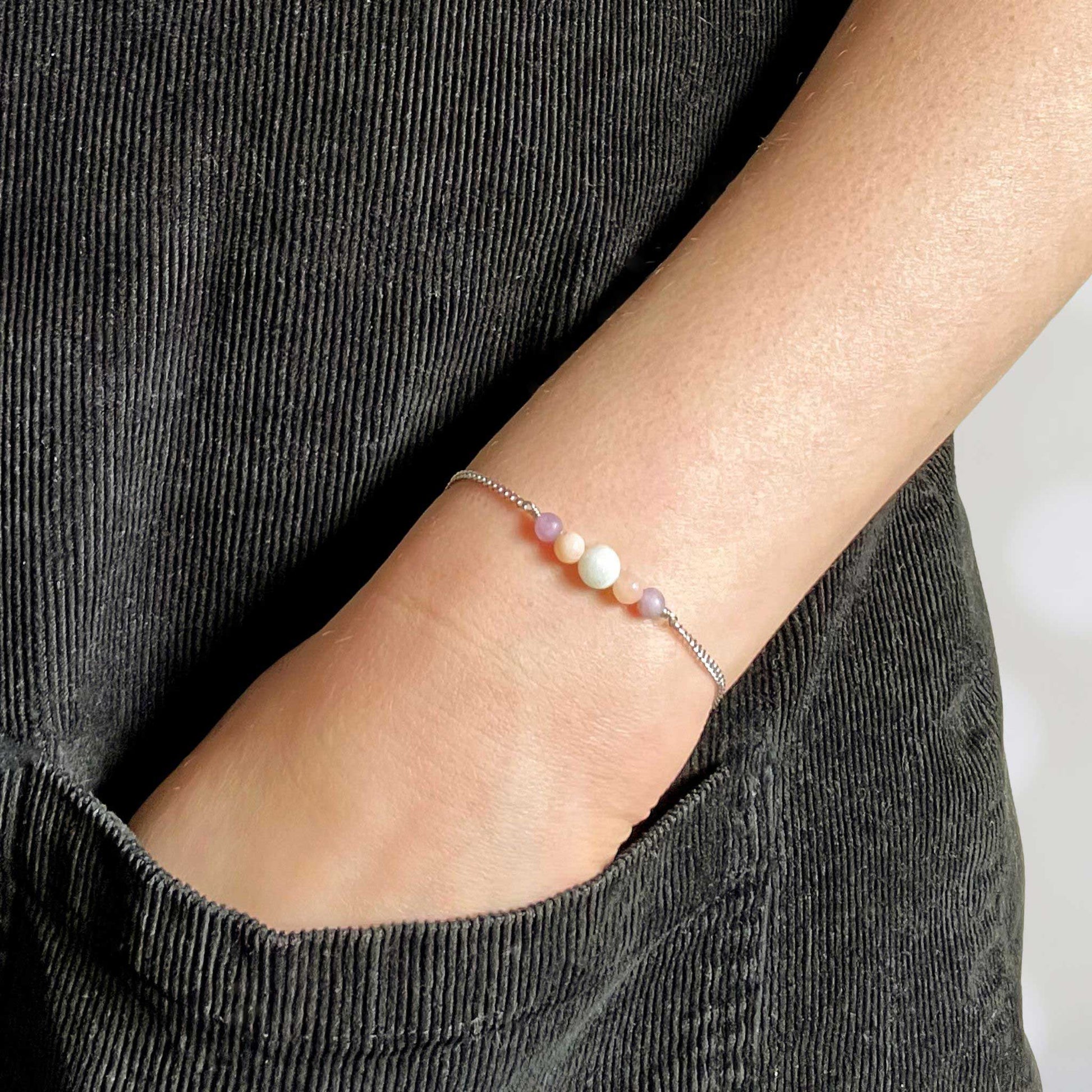 Woman with hand in pocket wearing pastel gemstone bracelet