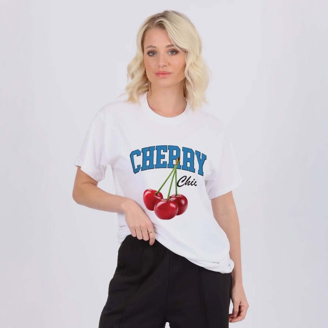 Person wearing a white t-shirt with 'CHERRY CHIC' text and cherry graphics on a plain background