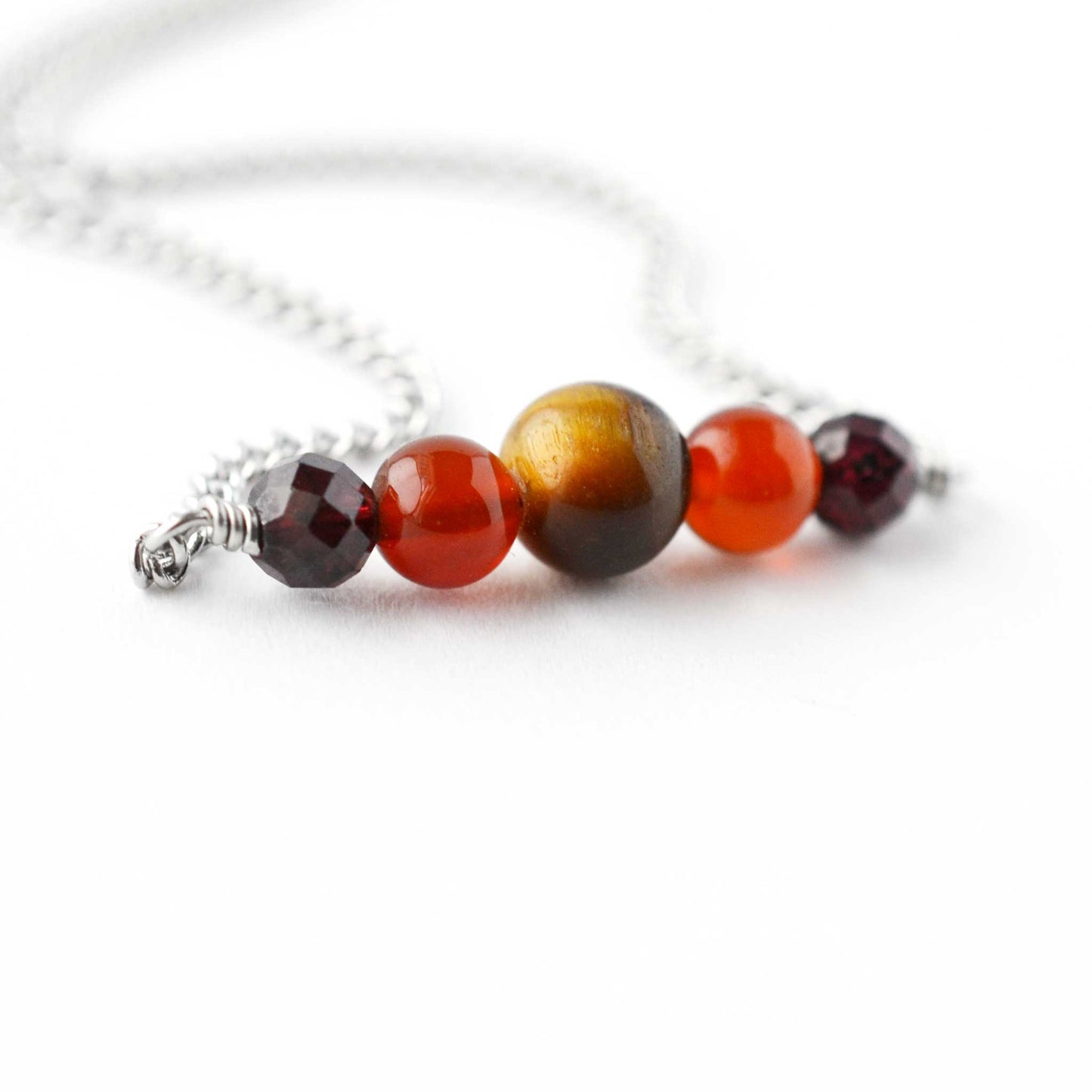 Close up of Tigers Eye, Carnelian & Garnet gemstones on stainless steel chain