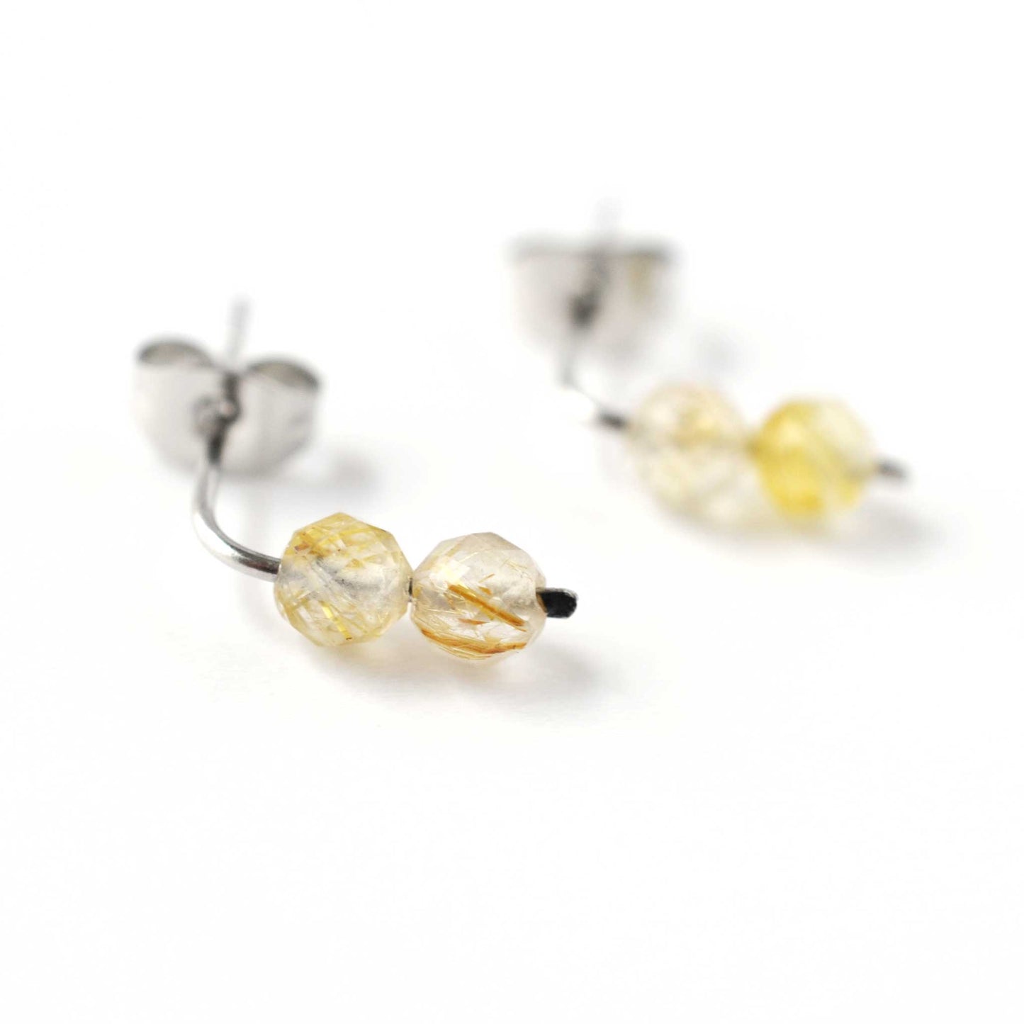 Close up of golden Rutilated Quartz gemstones on stud earrings