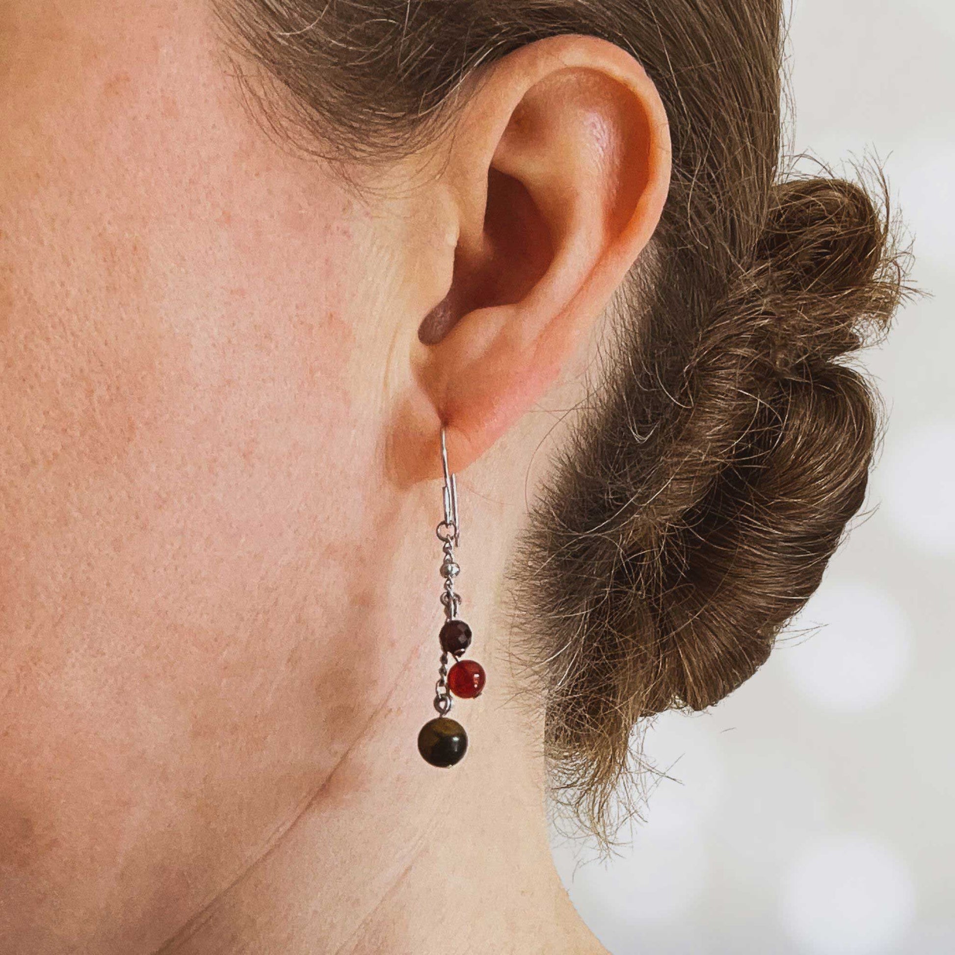 Woman wearing dark gemstone bead drop earring in earlobe
