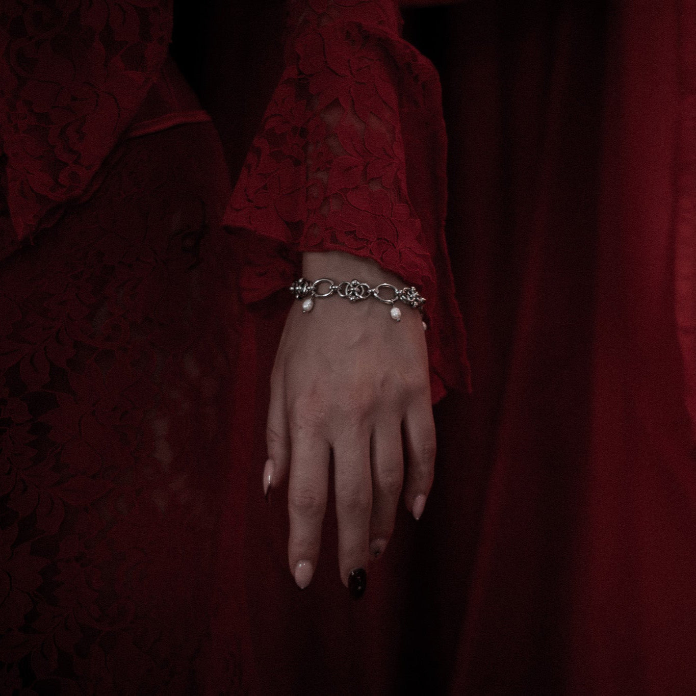 Hand wearing a bracelet with a dark red background