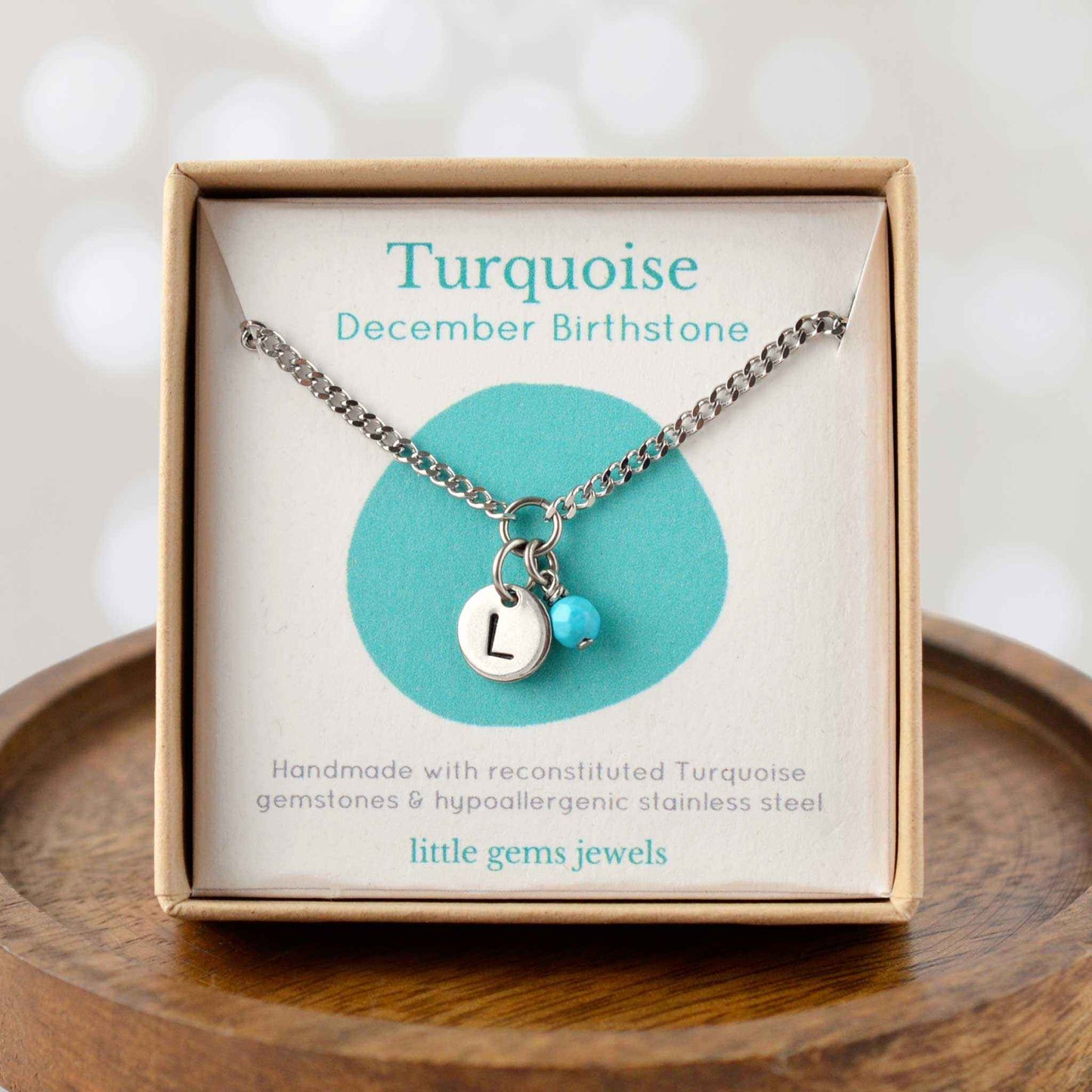 Turquoise December Birthstone necklace with hand stamped initial inside an eco-friendly gift box sitting on wooden coaster