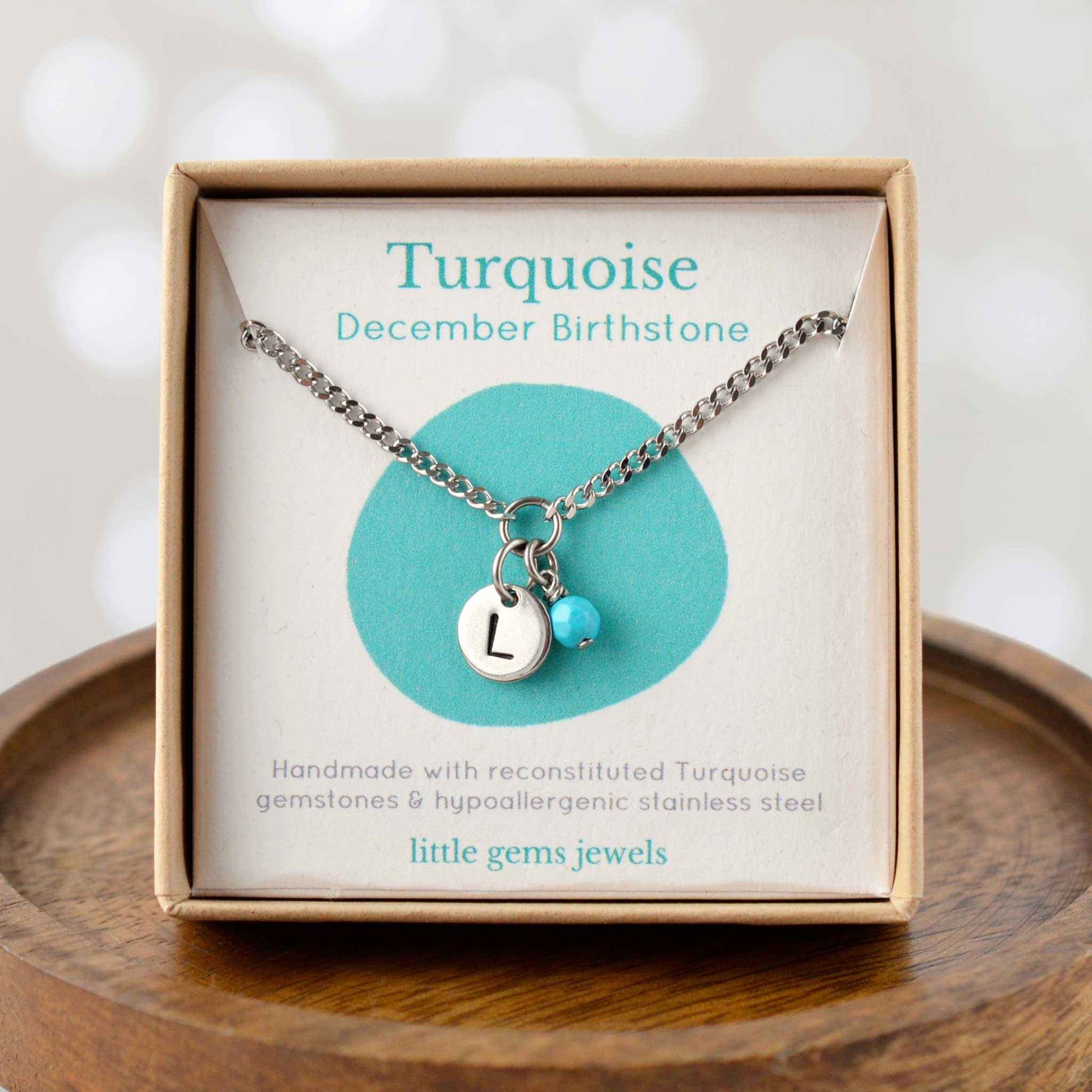 Turquoise December Birthstone necklace with hand stamped initial inside an eco-friendly gift box sitting on wooden coaster