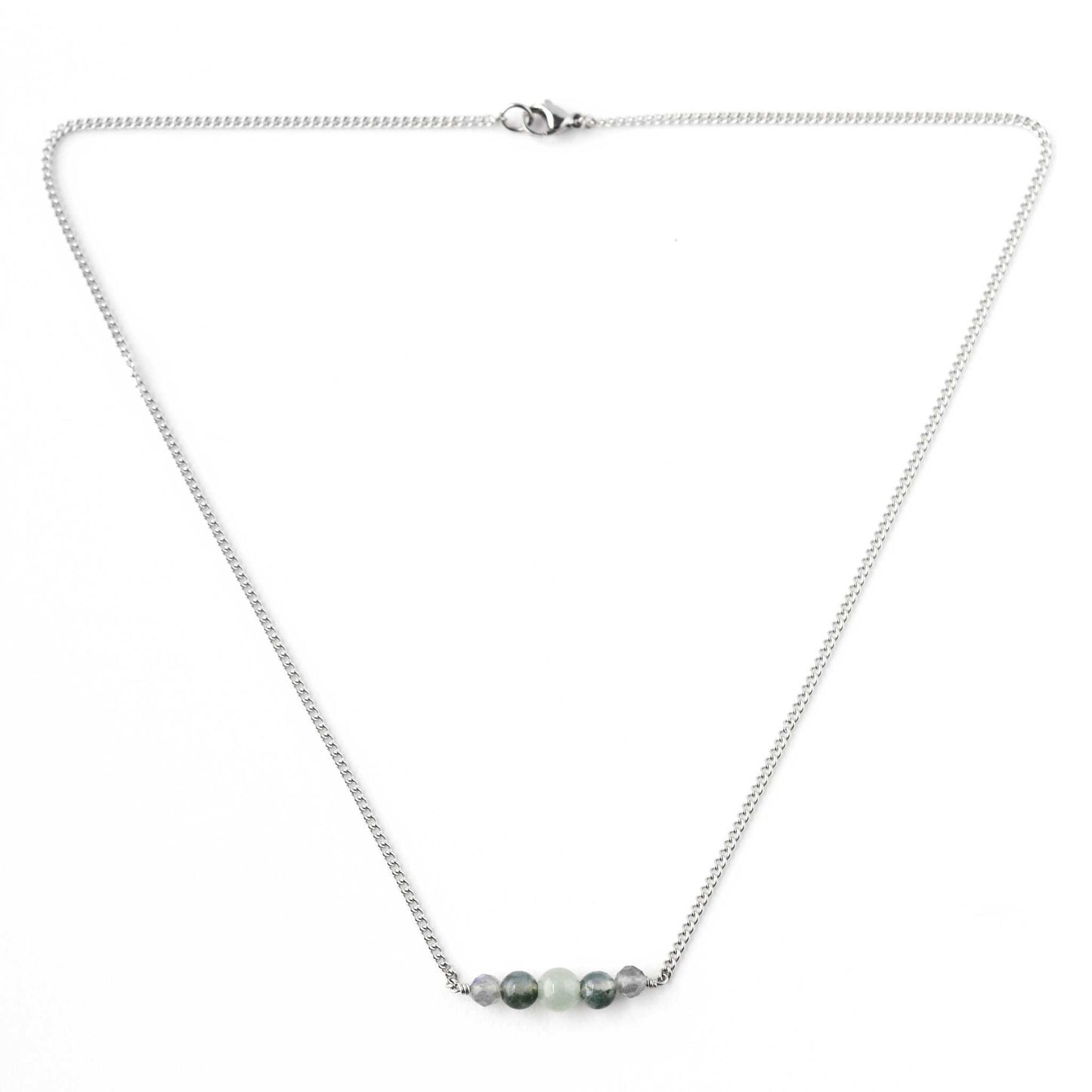 Flatlay of dainty green gemstone necklace with stainless steel chain and lobster clasp