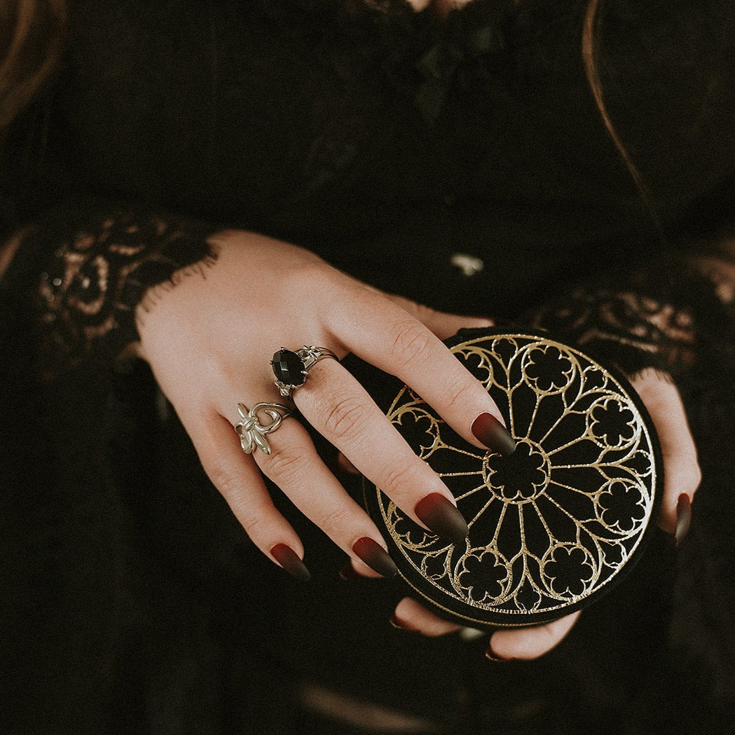 Hand holding a round, intricately designed box with detailed patterns.