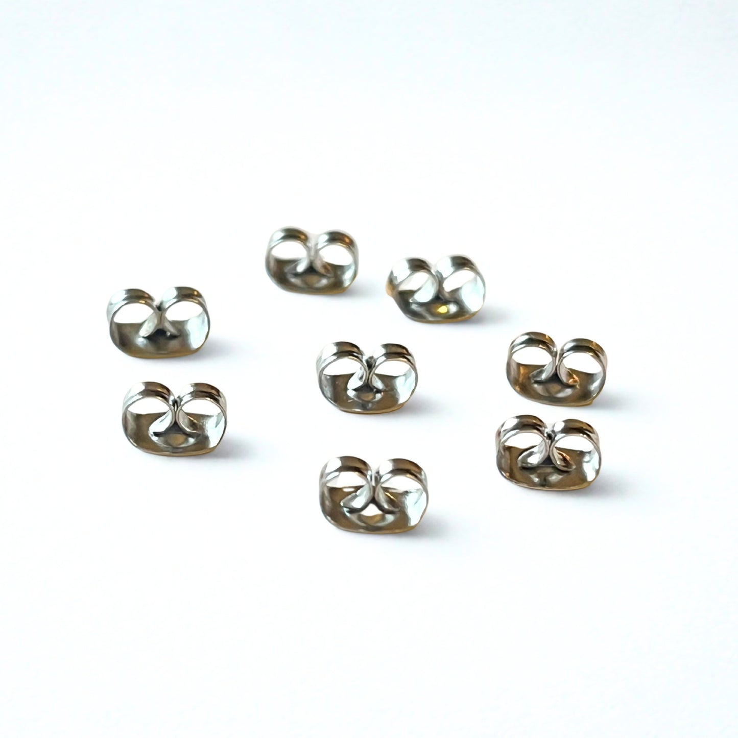Set of eight surgical steel butterfly earring backs on a white background