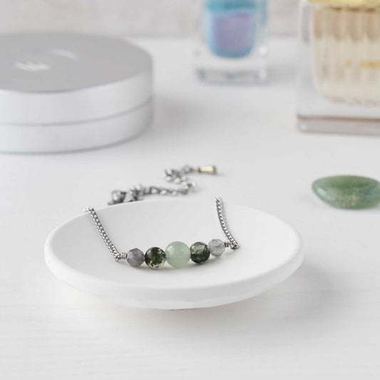 Green gemstone bracelet in trinket dish on dressing table