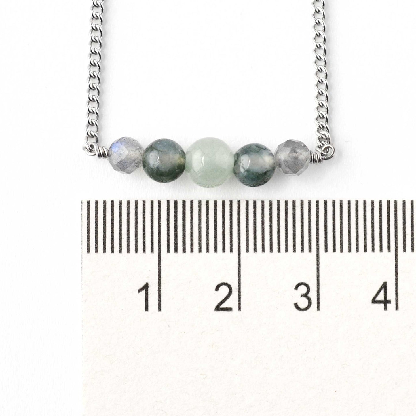 Dainty green gemstone bracelet next to ruler