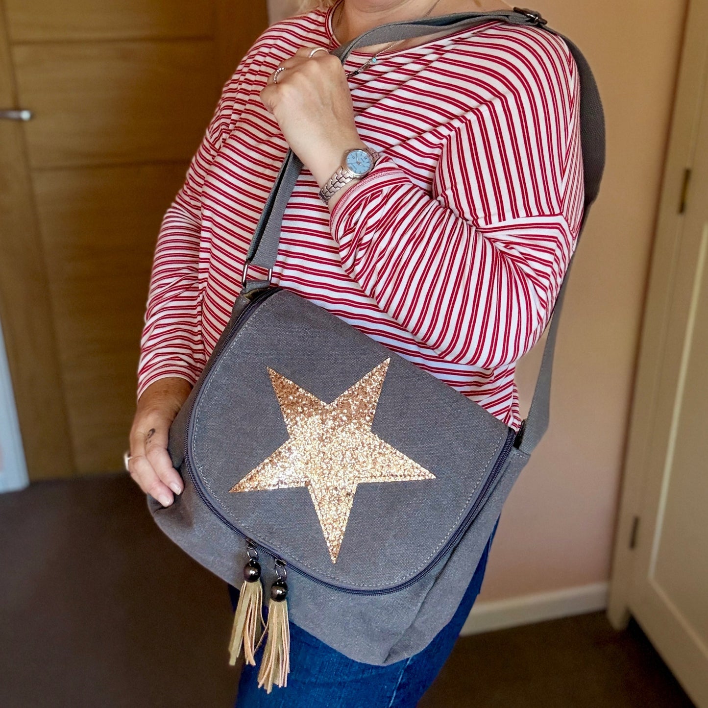 Woman holding a gray bag with a star design indoors.