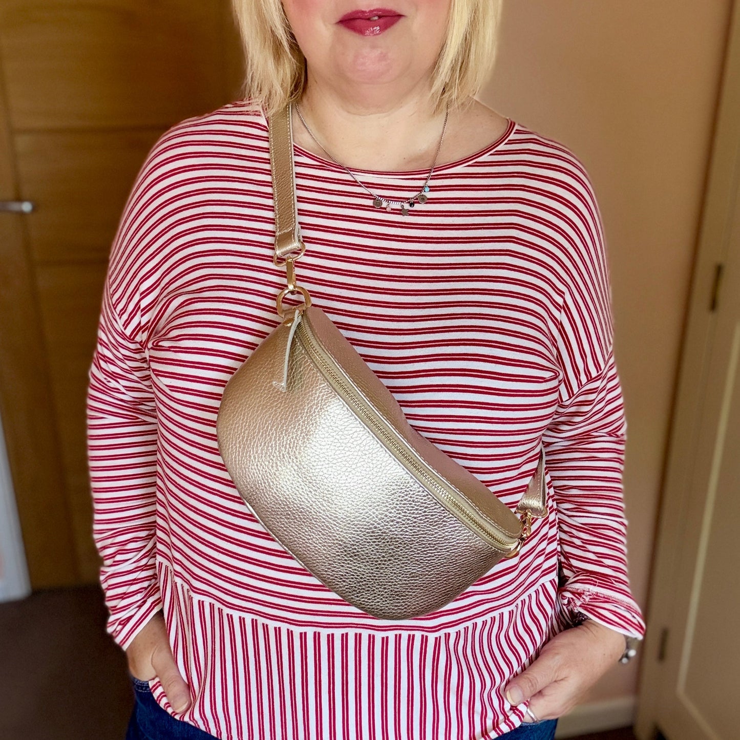 Woman wearing a red and white striped shirt with a gold crossbody bag indoors.