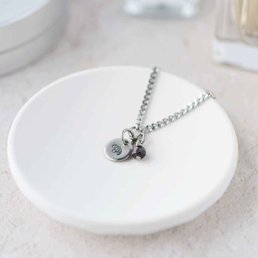 Tiny Carnation & Garnet gemstone necklace laying in white trinket dish