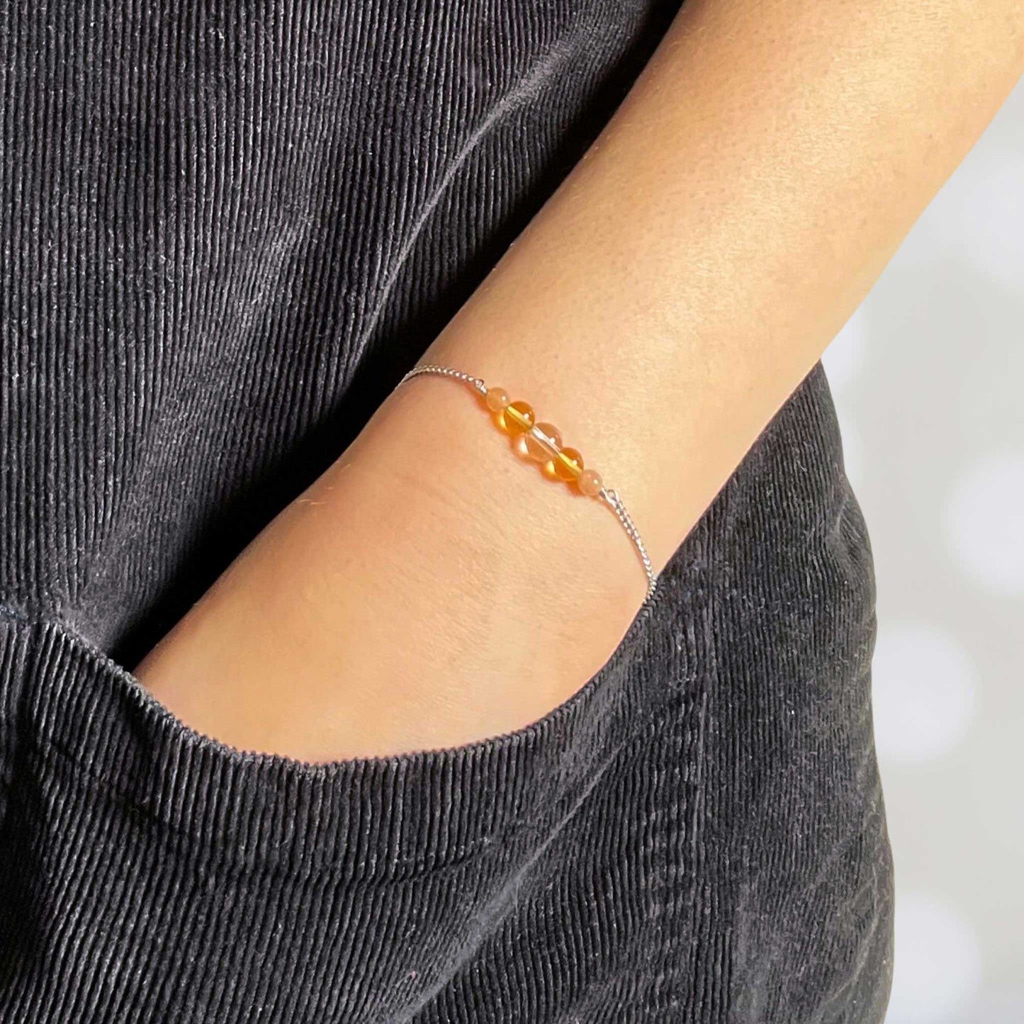 Woman with hand in pocket wearing dainty yellow gemstone bracelet
