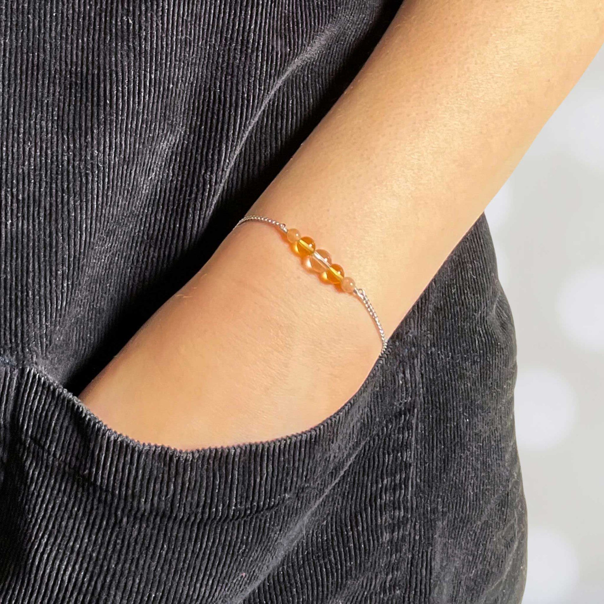 Woman with hand in pocket wearing dainty yellow gemstone bracelet