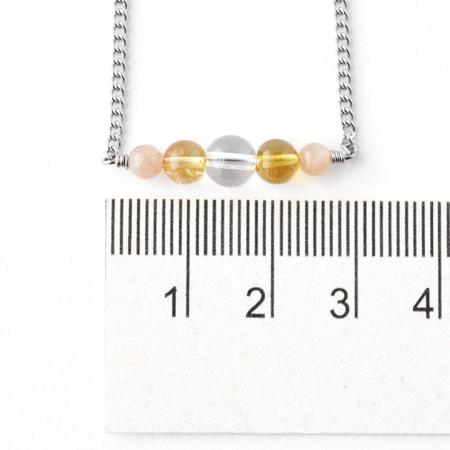 Yellow gemstone bar necklace next to ruler