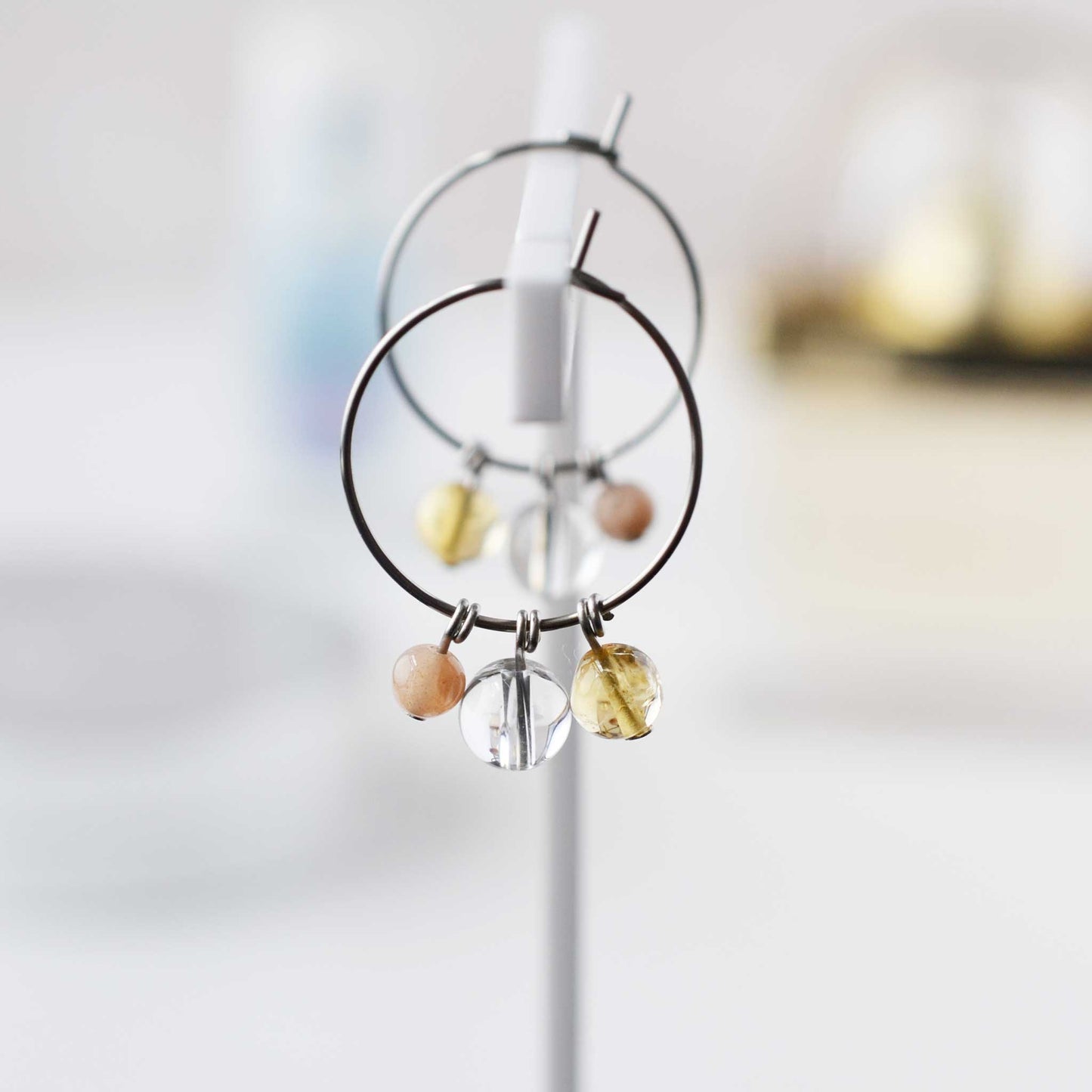 Yellow gemstone hoop earrings hanging against soft focus background