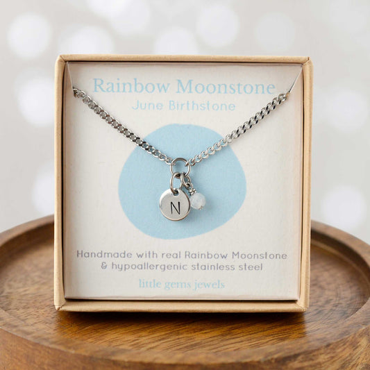 Rainbow Moonstone June Birthstone necklace with hand stamped initial inside an eco-friendly gift box sitting on wooden coaster