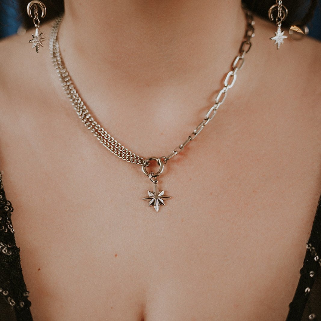 Close-up of a steel chain necklace with star pendant and matching earrings.