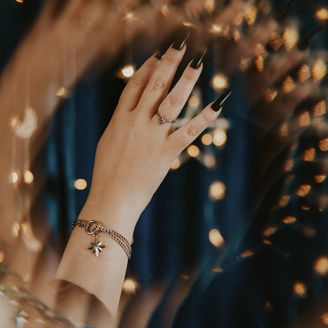 Hand with a ring and bracelet against a blurred background of lights