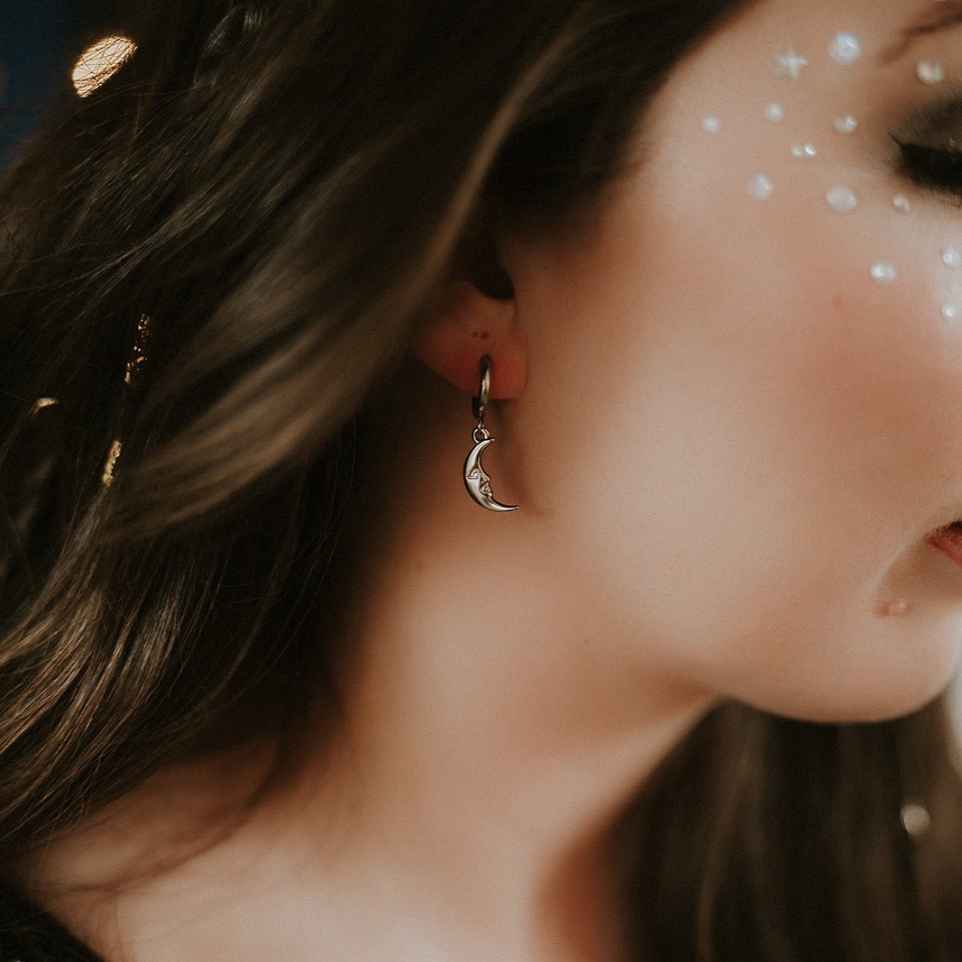 Close-up of a woman wearing a moon-shaped earring with blurred background