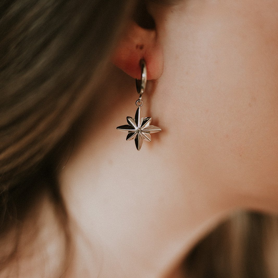 Close-up of a person wearing a silver star-shaped earring.