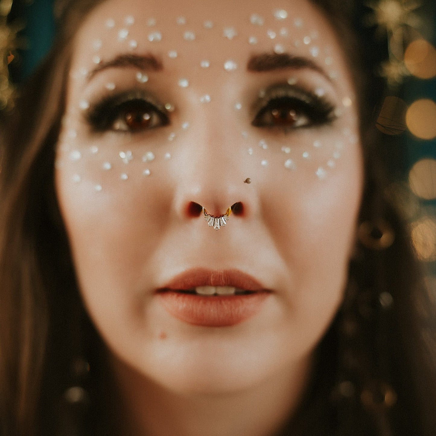 Close-up of a person with decorative face makeup and a blurred bokeh background
