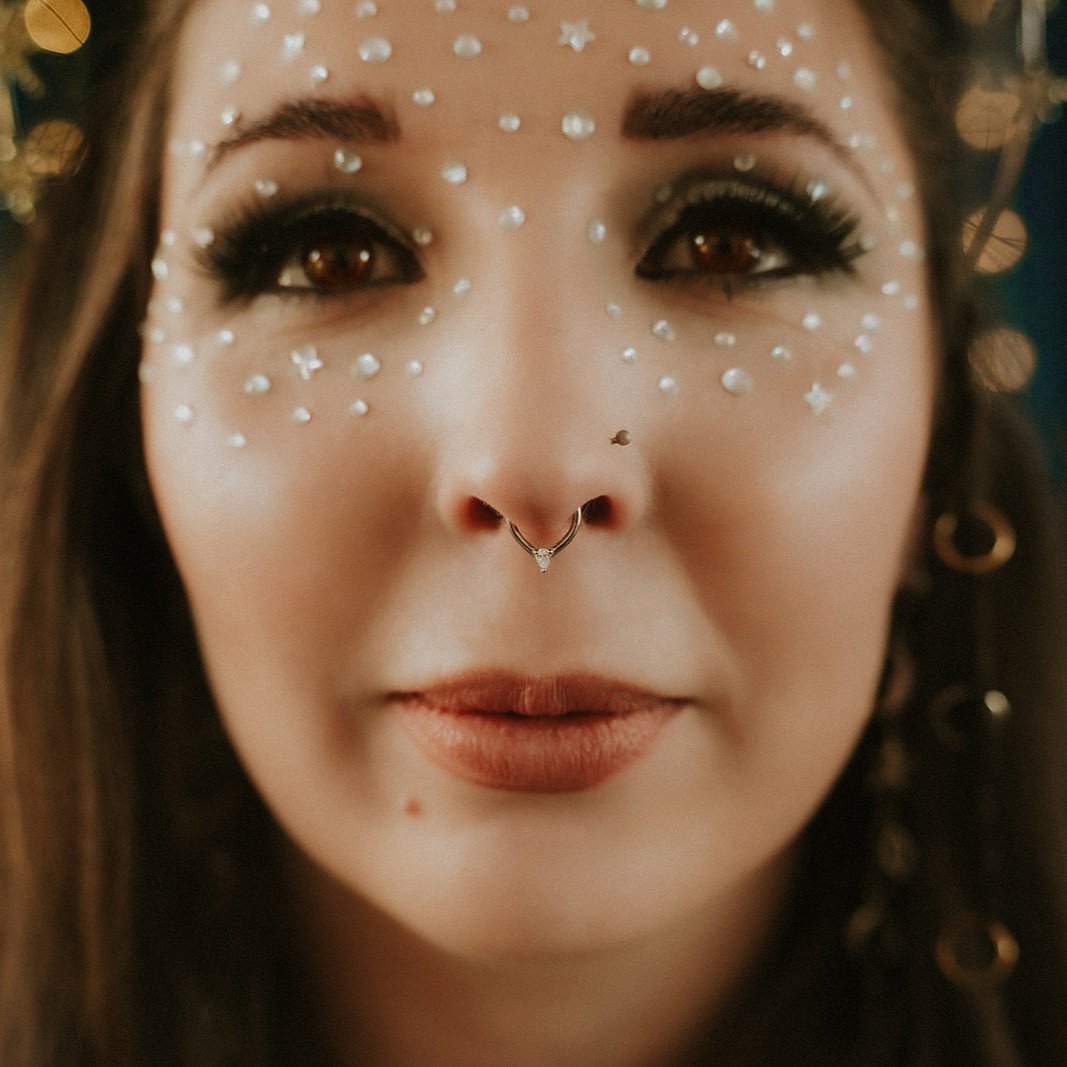 Close-up of a woman's face with decorative elements and a nose ring.