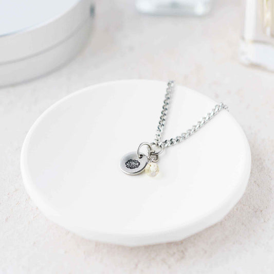 Tiny Chrysanthemum & Citrine gemstone necklace laying in white trinket dish