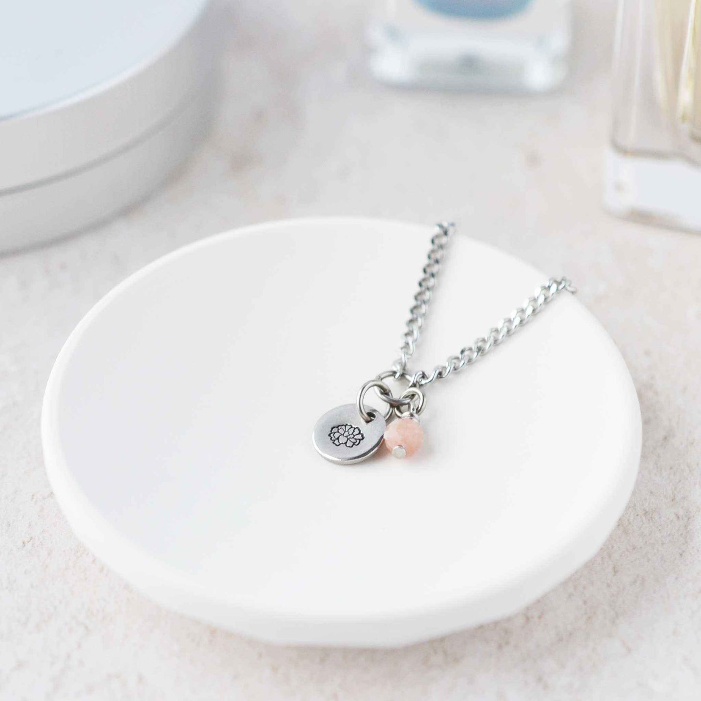 Tiny Marigold & Pink Opal gemstone necklace laying in white trinket dish