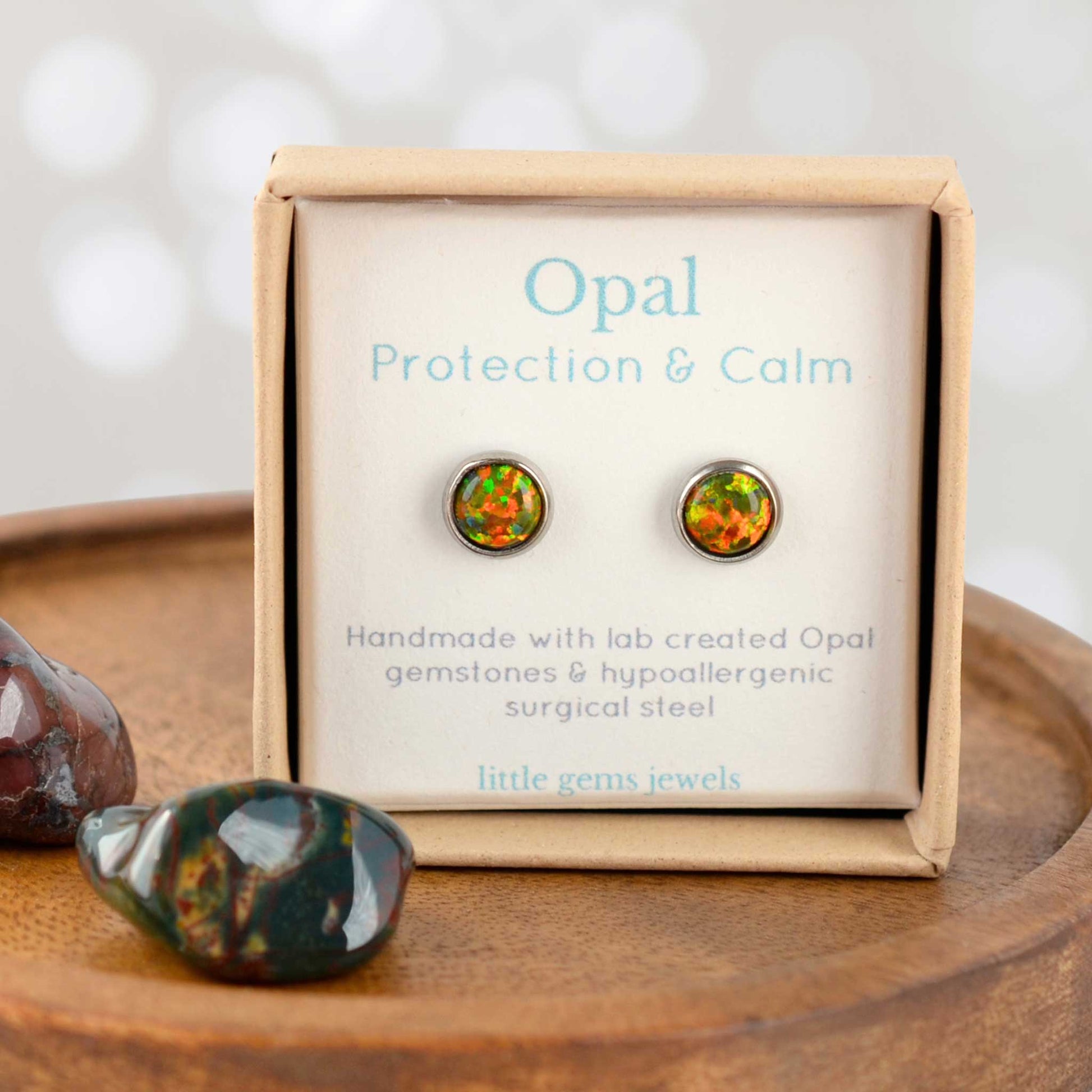 Opal earrings in a 'Protection & Calm' box with stones on a wooden surface
