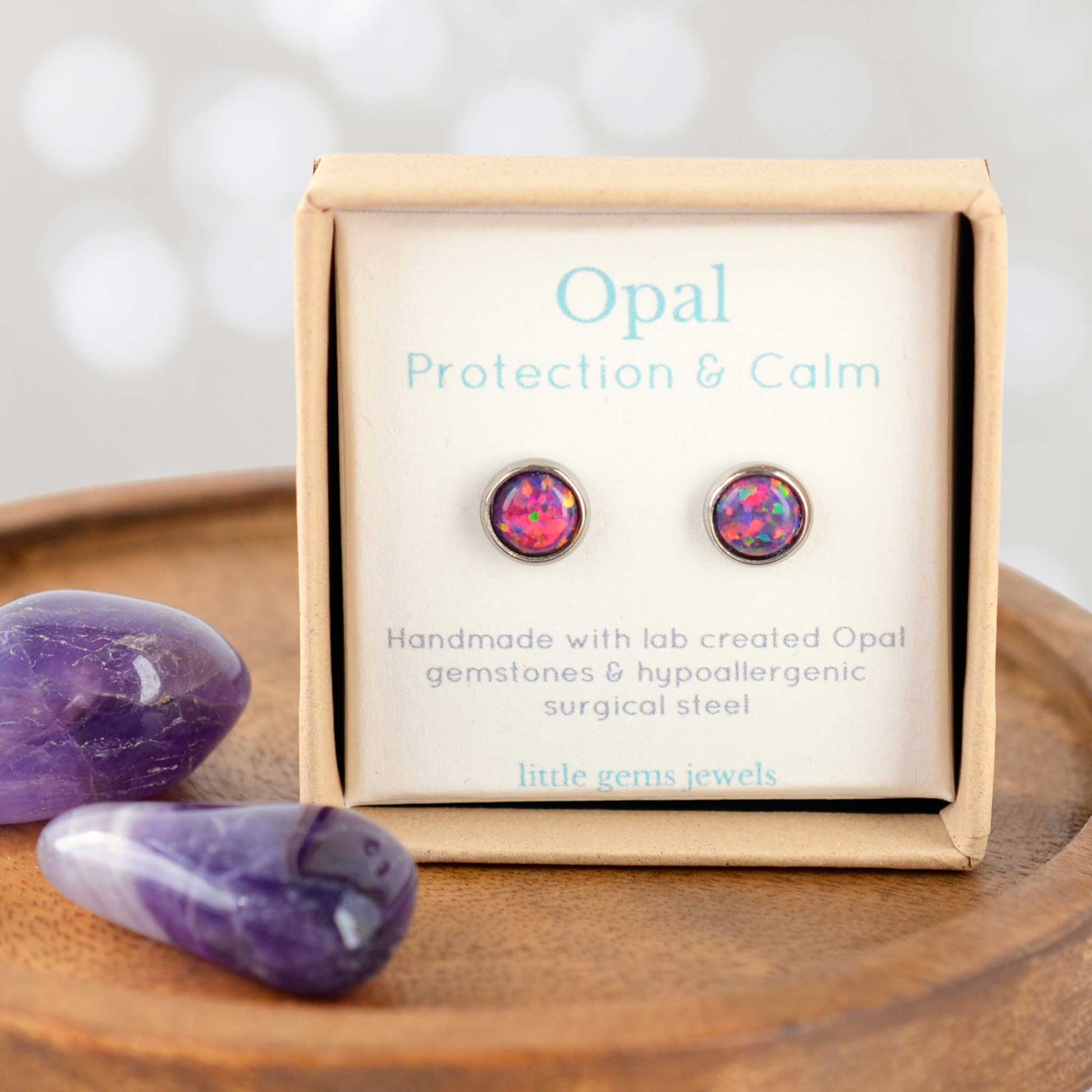 Opal earrings in a box with purple stones on a wooden surface