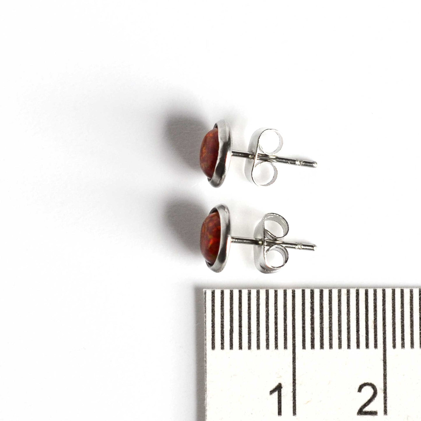 Red Opal stud earrings next to ruler
