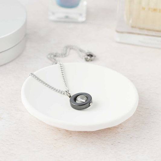 Rock Crystal gemstone pendant necklace laying in white trinket dish.